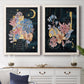 Set of two white barnwood framed canvas prints depicting a coordinated art pair of fantastical bouquets and celestial symbols on black rendered as whimsical floral collages above a dining room sideboard.