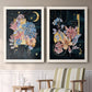 Set of two white barnwood framed canvas prints depicting two whimsical floral collages featuring fantastical bouquets and celestial symbols on black above a sideboard in a cozy sitting room.