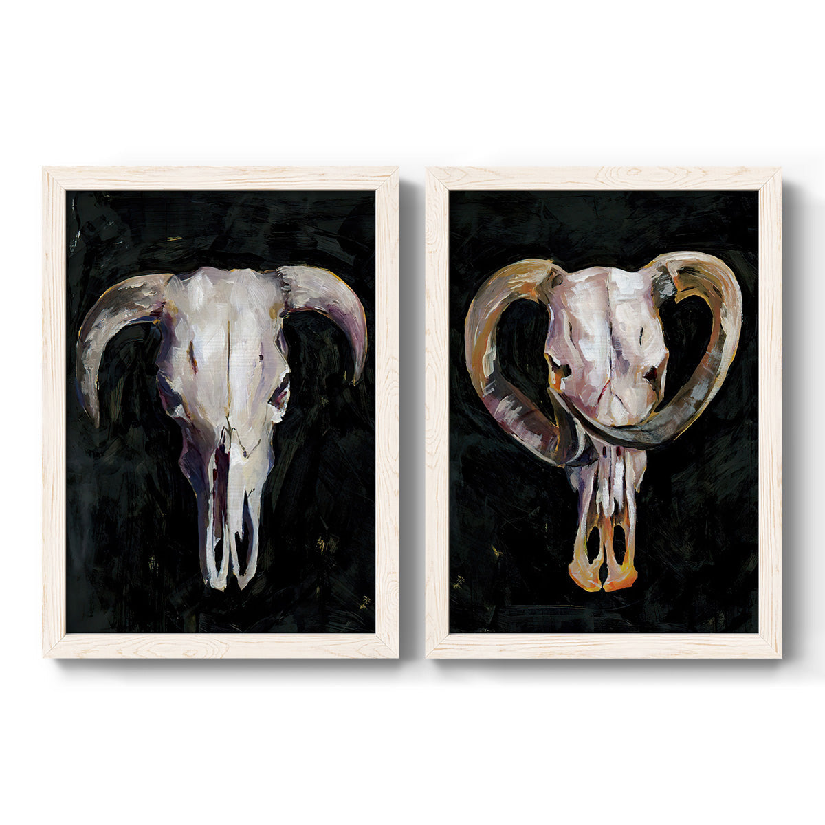 Set of two white barnwood framed canvas prints featuring two dramatic Western animal paintings featuring ram and cattle skulls against black grounds.