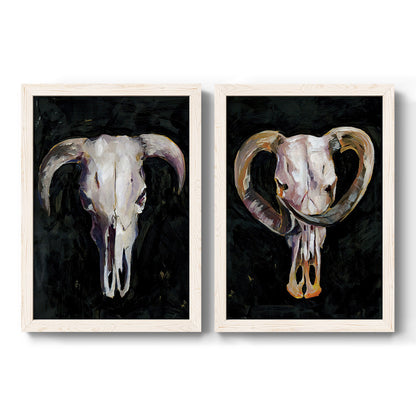 Set of two white barnwood framed canvas prints featuring two dramatic Western animal paintings featuring ram and cattle skulls against black grounds.