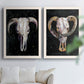 Set of two white barnwood framed canvas prints depicting curved horns, bone-white forms, and expressive dark brushwork arranged across two complementary compositions above a sofa in a bright living space.