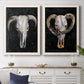 Set of two white barnwood framed canvas prints depicting a coordinated art pair of ram and cattle skulls against black grounds rendered as dramatic Western animal paintings above a dining room sideboard.