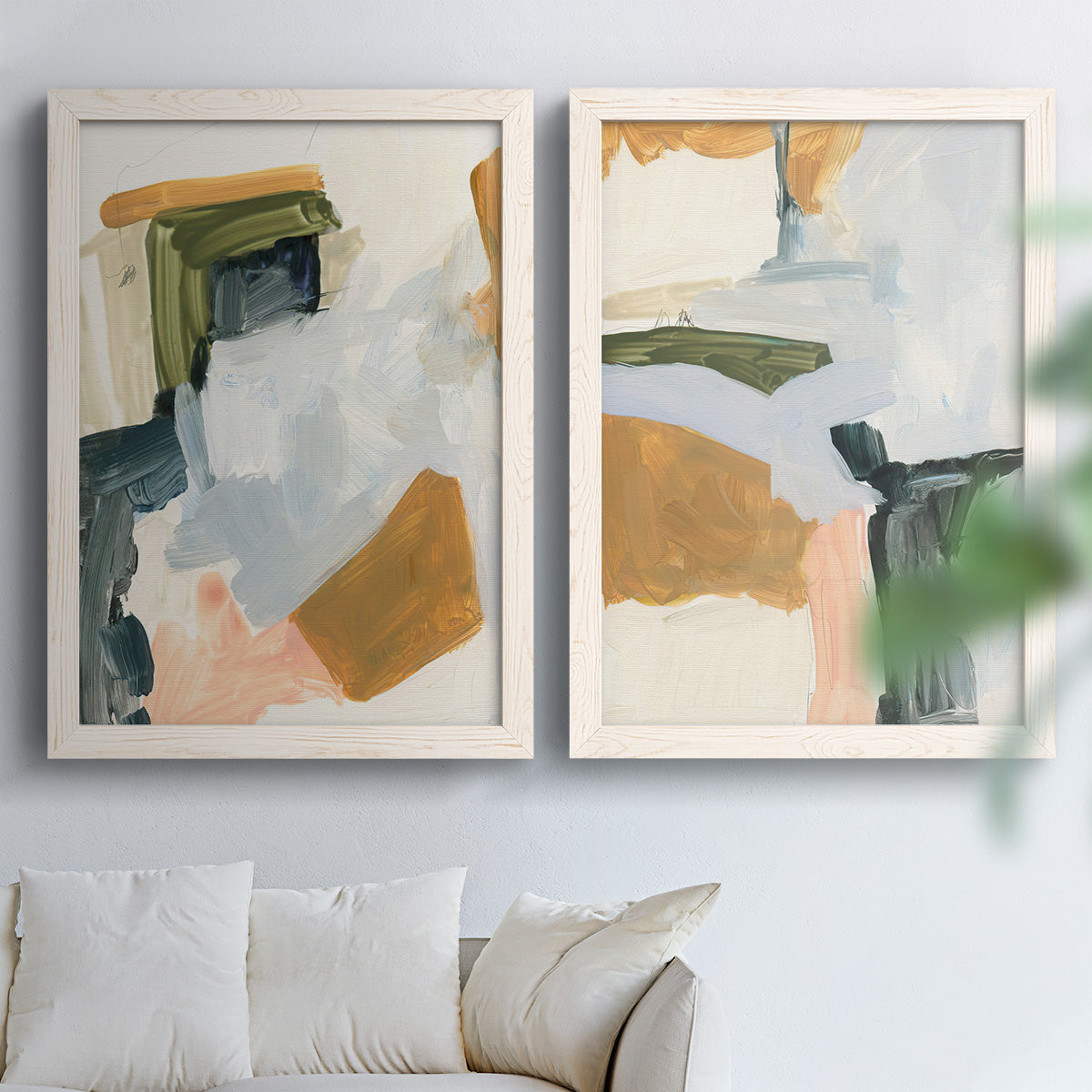 Set of two white barnwood framed canvas prints depicting broad geometric marks, soft overlaps, and restrained warm accents arranged across two complementary compositions above a sofa in a bright living space.