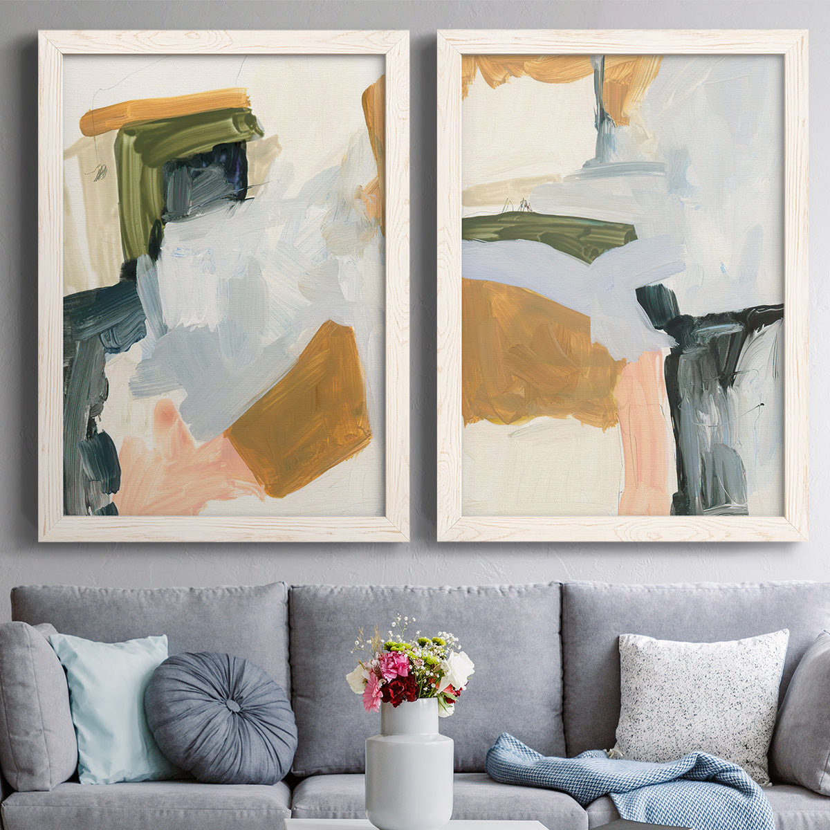 Set of two white barnwood framed canvas prints depicting paired contemporary mixed-media abstracts with broad geometric marks, soft overlaps, and restrained warm accents above a sofa in a contemporary living room.