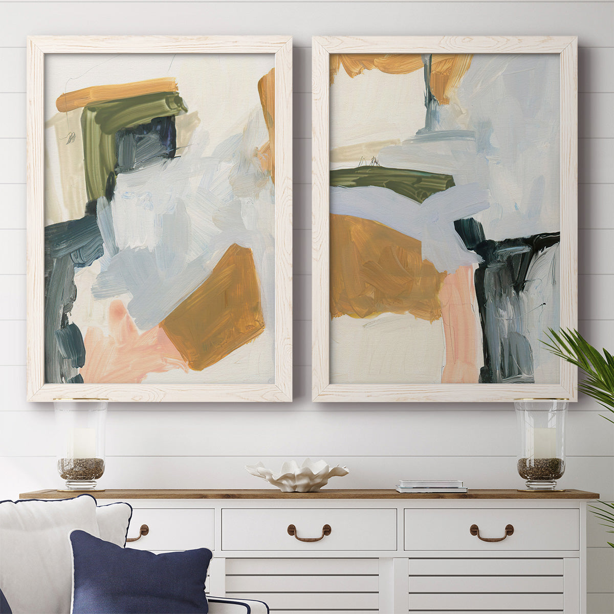 Set of two white barnwood framed canvas prints depicting a coordinated art pair of layered green ochre blush gray and white paint blocks rendered as contemporary mixed-media abstracts above a dining room sideboard.