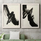Set of two white barnwood framed canvas prints depicting a coordinated art pair of sweeping black calligraphic brushstrokes rendered as bold gestural abstracts above a sofa in a modern living room.