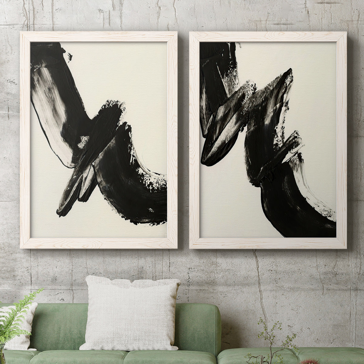 Set of two white barnwood framed canvas prints depicting a coordinated art pair of sweeping black calligraphic brushstrokes rendered as bold gestural abstracts above a sofa in a modern living room.