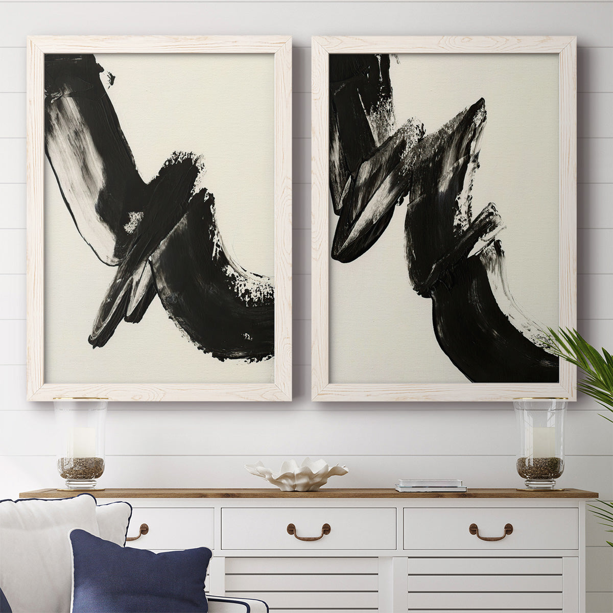 Set of two white barnwood framed canvas prints depicting a coordinated art pair of sweeping black calligraphic brushstrokes rendered as bold gestural abstracts above a dining room sideboard.