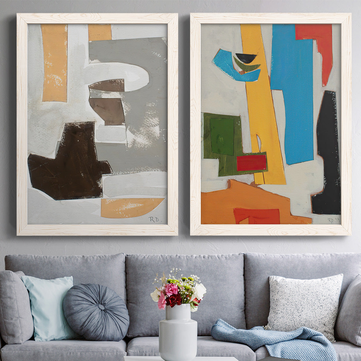 Set of two white barnwood framed canvas prints depicting paired mid-century geometric abstracts with rectangles arcs and angular sections with bold color contrasts above a sofa in a contemporary living room.