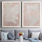 Set of two white barnwood framed canvas prints depicting paired minimalist color-field abstracts with cloudy rose washes, broad pale strokes, and subtle texture above a sofa in a contemporary living room.