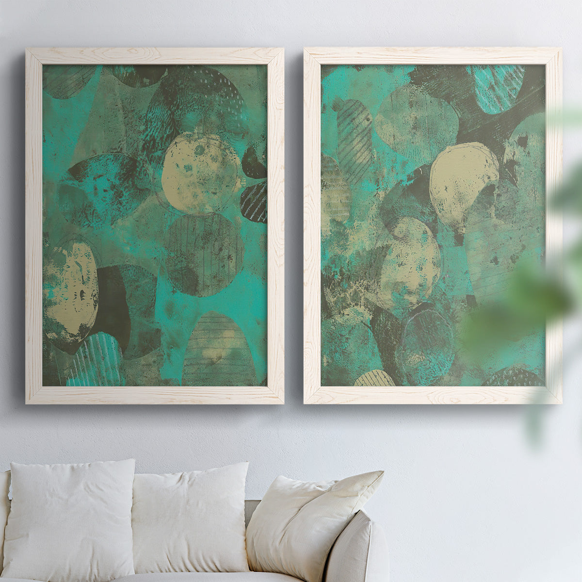 Set of two white barnwood framed canvas prints depicting overlapping orbs, translucent prints, and weathered green grounds arranged across two complementary compositions above a sofa in a bright living space.