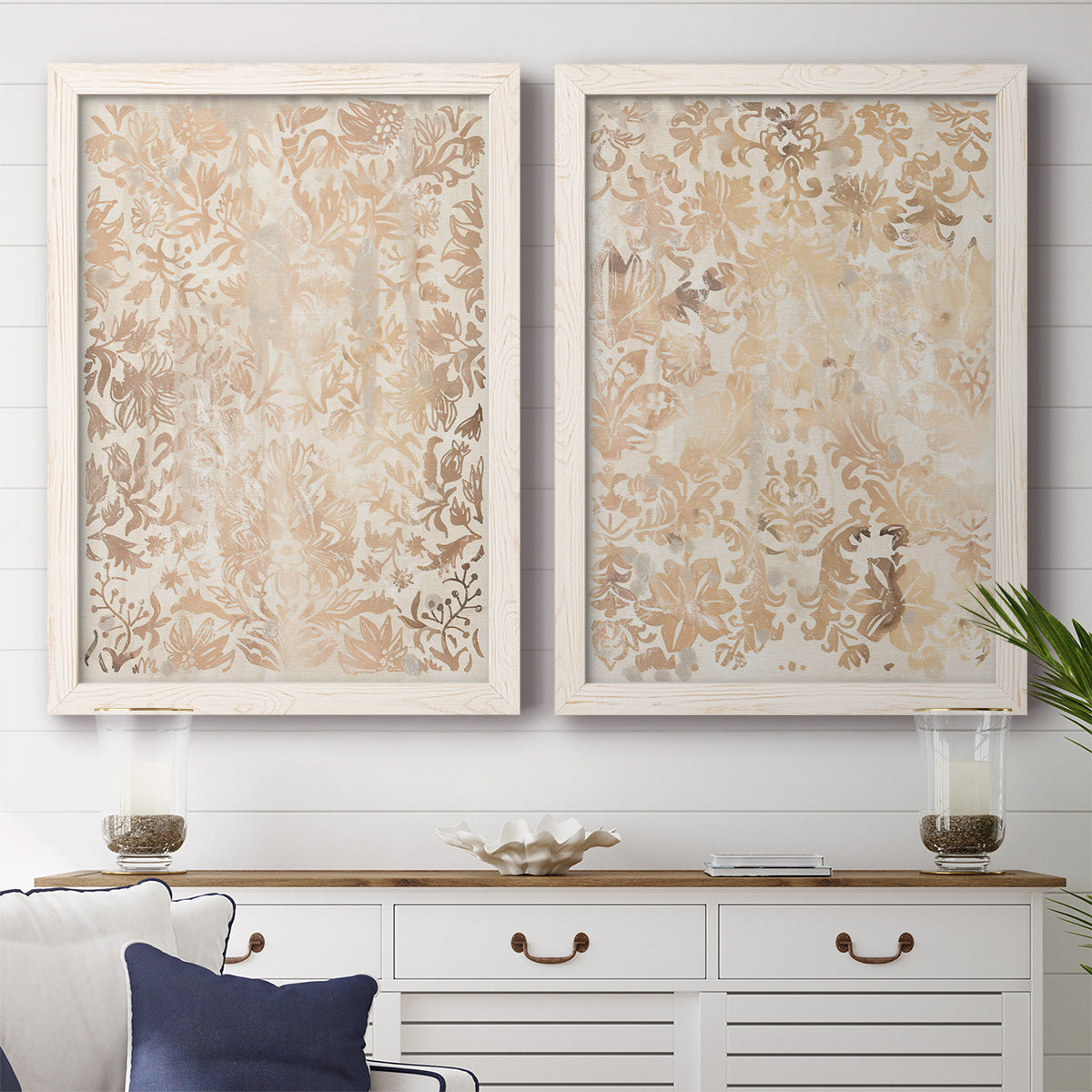 Set of two white barnwood framed canvas prints depicting a coordinated art pair of ornate cream floral damask patterns rendered as vintage decorative prints above a dining room sideboard.