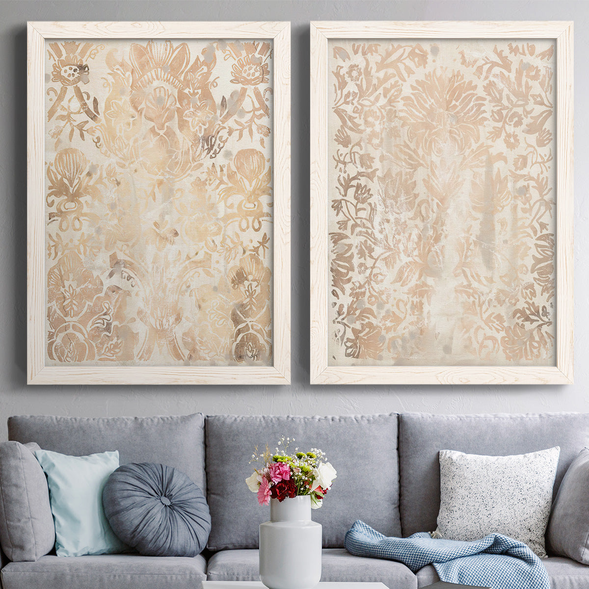Set of two white barnwood framed canvas prints depicting paired vintage decorative prints with dense scrolling foliage, distressed walnut-brown texture, and symmetrical motifs above a sofa in a contemporary living room.