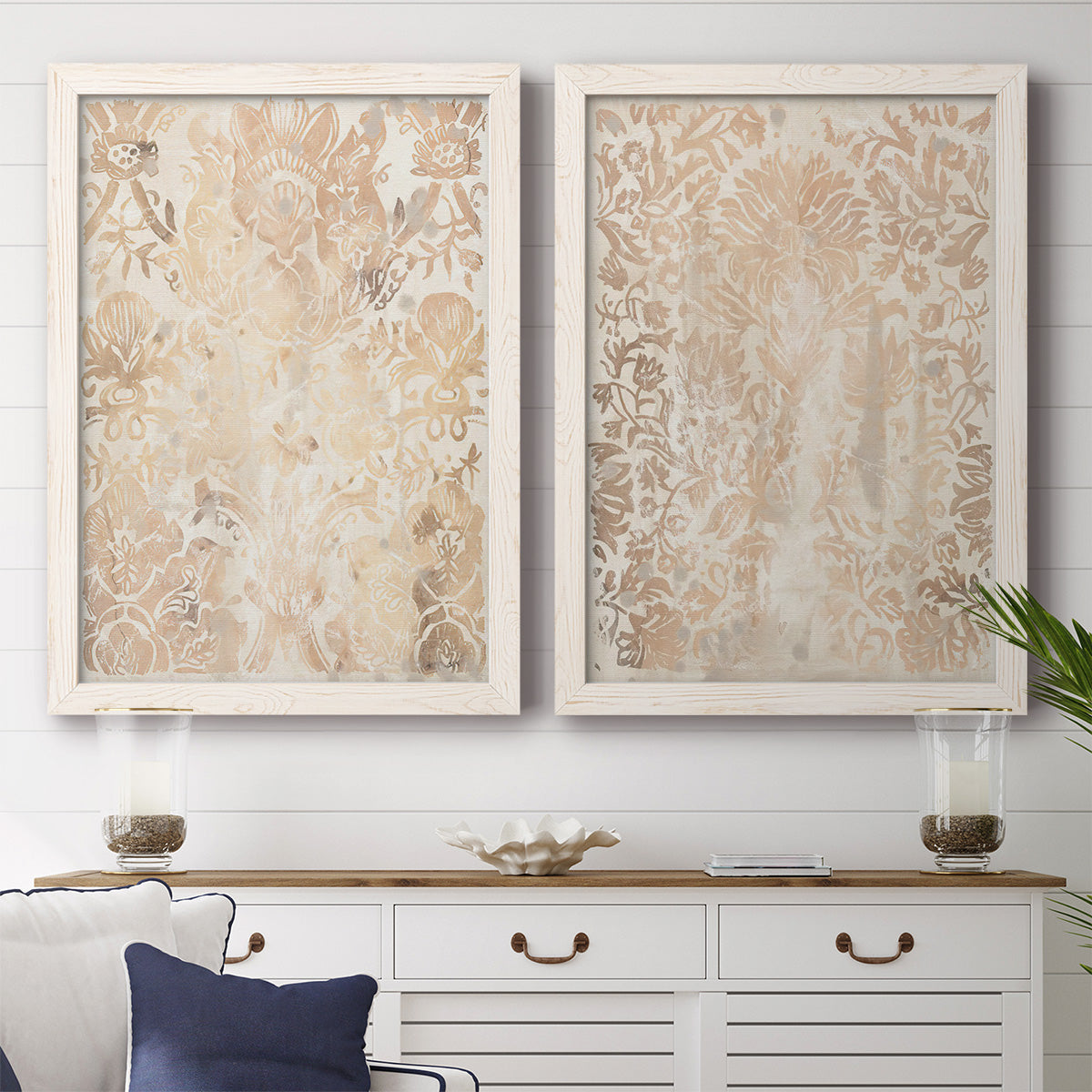Set of two white barnwood framed canvas prints depicting a coordinated art pair of ornate cream floral damask patterns rendered as vintage decorative prints above a dining room sideboard.