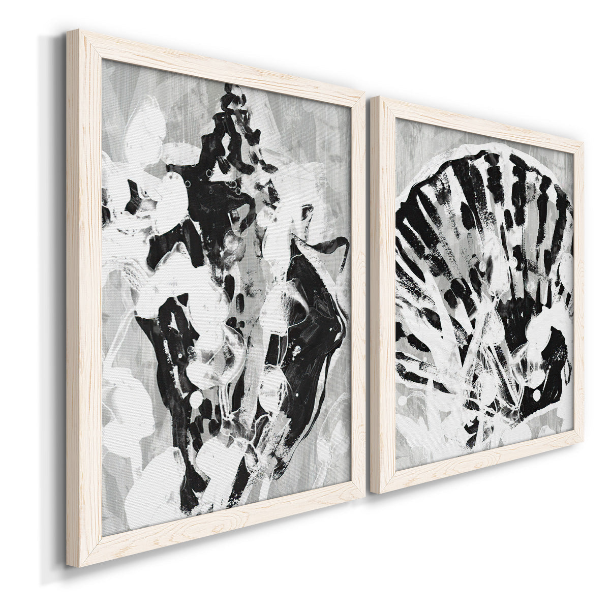 Angled view of a set of two white barnwood framed canvas prints featuring two dramatic monochrome abstracts featuring black and gray inkblot bursts.