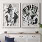 Set of two white barnwood framed canvas prints depicting a coordinated art pair of black and gray inkblot bursts rendered as dramatic monochrome abstracts above a dining room sideboard.