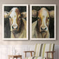 Set of two white barnwood framed canvas prints depicting two painterly farm-animal portraits featuring close-up portraits of gentle brown cows above a sideboard in a cozy sitting room.