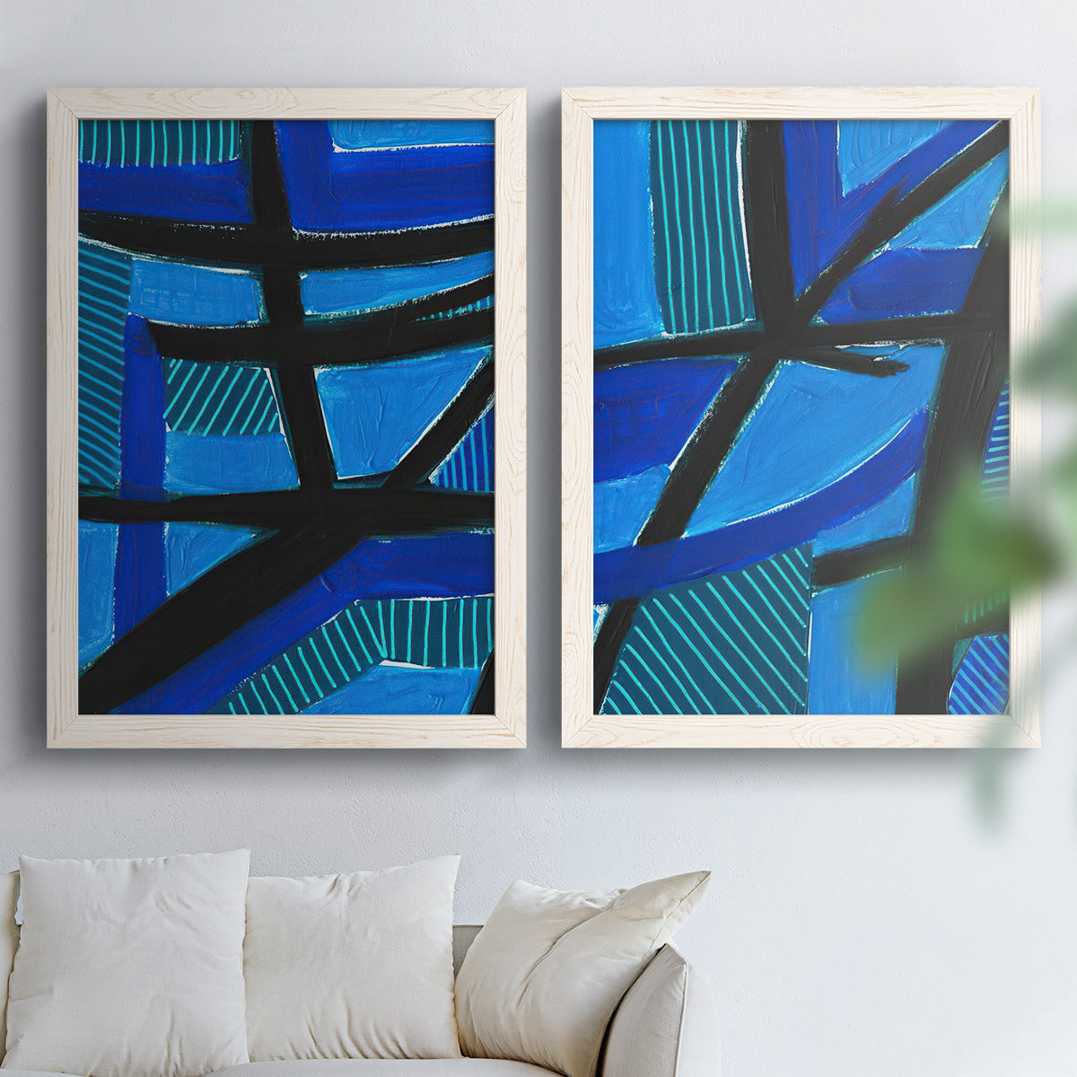 Set of two white barnwood framed canvas prints depicting cobalt turquoise and navy sections with strong diagonal structure arranged across two complementary compositions above a sofa in a bright living space.