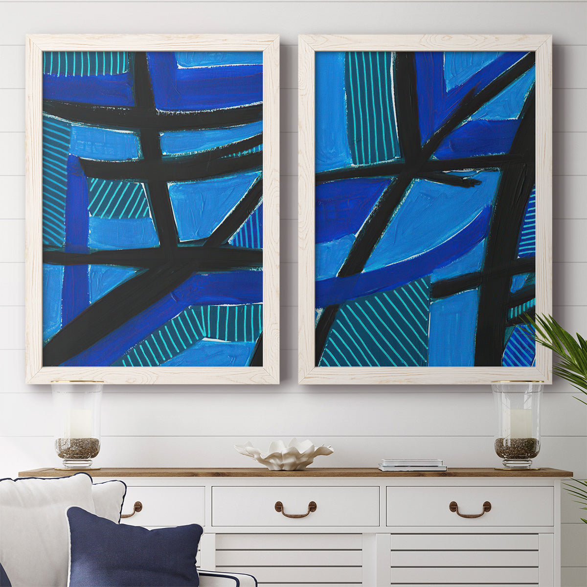 Set of two white barnwood framed canvas prints depicting a coordinated art pair of intersecting black bars over vivid blue fields rendered as bold geometric abstracts above a dining room sideboard.