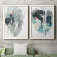 Set of two white barnwood framed canvas prints depicting a coordinated art pair of large black gray and teal circular gestures rendered as bold gestural abstracts above a sofa in a modern living room.