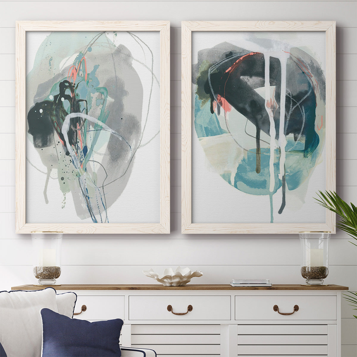 Set of two white barnwood framed canvas prints depicting a coordinated art pair of large black gray and teal circular gestures rendered as bold gestural abstracts above a dining room sideboard.