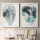 Set of two white barnwood framed canvas prints depicting two bold gestural abstracts featuring large black gray and teal circular gestures above a sideboard in a cozy sitting room.
