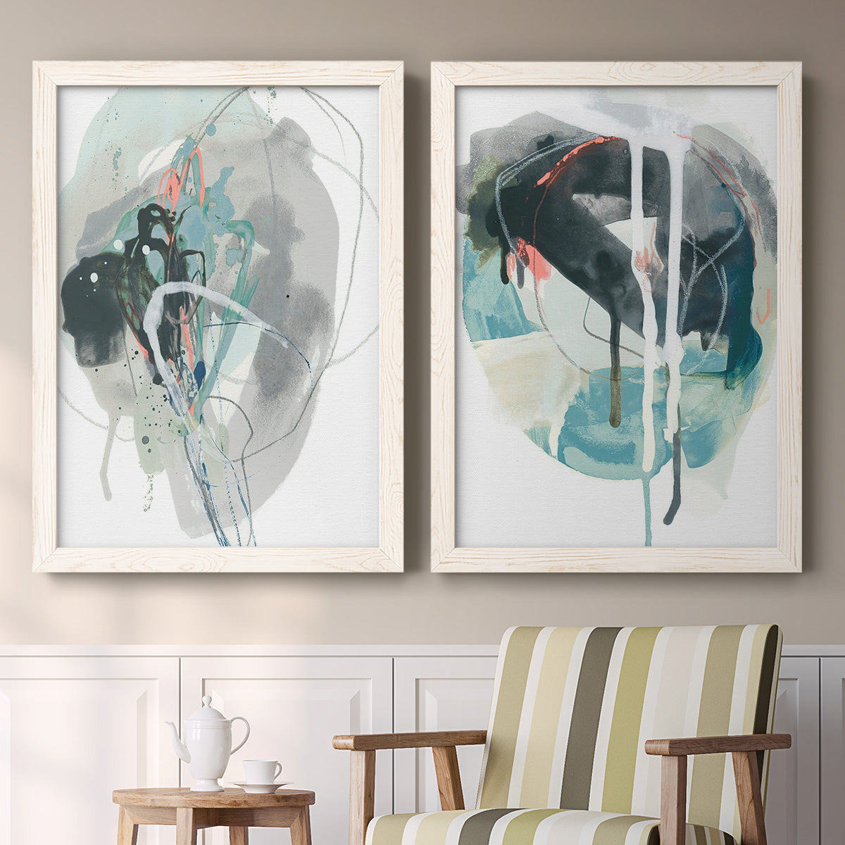 Set of two white barnwood framed canvas prints depicting two bold gestural abstracts featuring large black gray and teal circular gestures above a sideboard in a cozy sitting room.