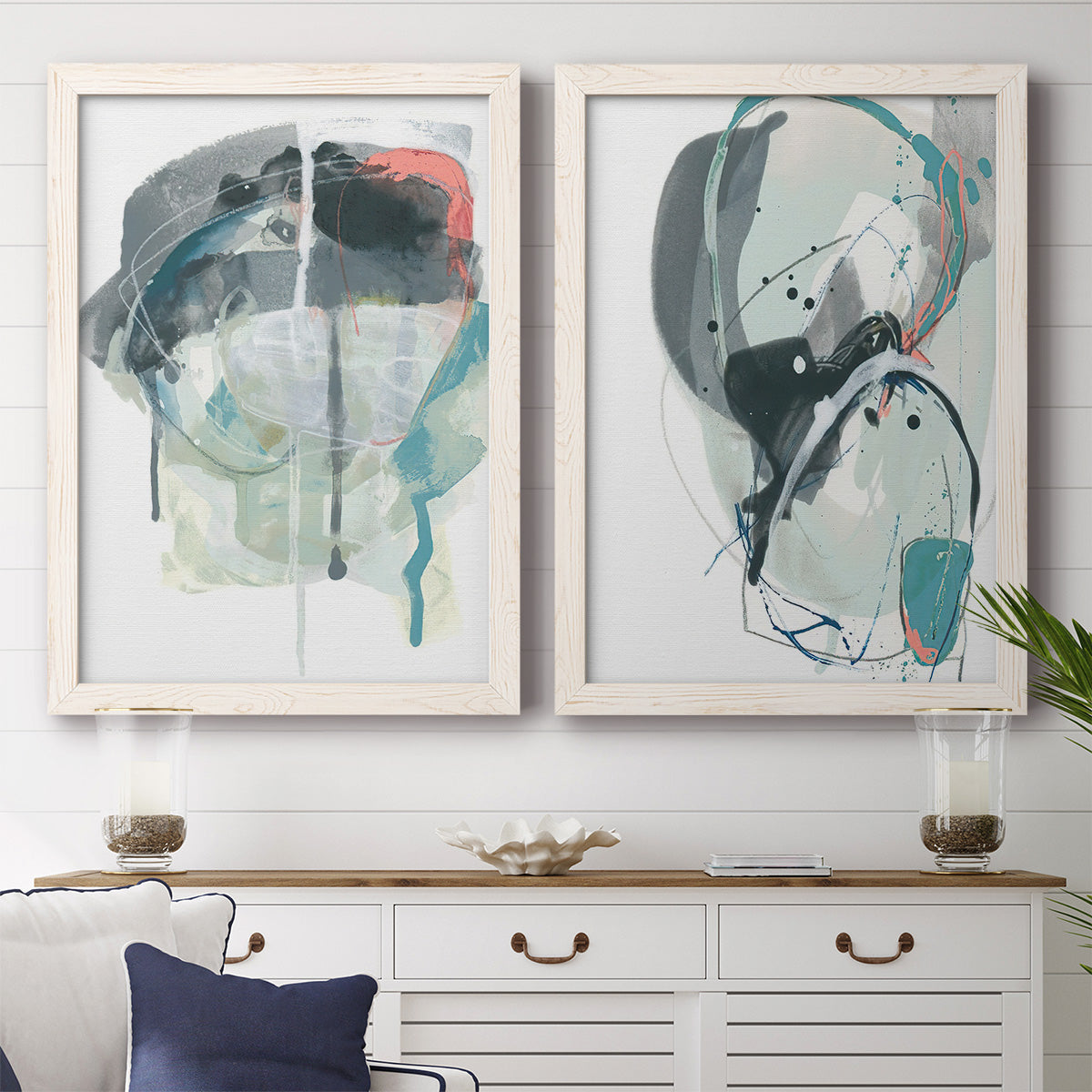 Set of two white barnwood framed canvas prints depicting a coordinated art pair of large black gray and teal circular gestures rendered as bold gestural abstracts above a dining room sideboard.