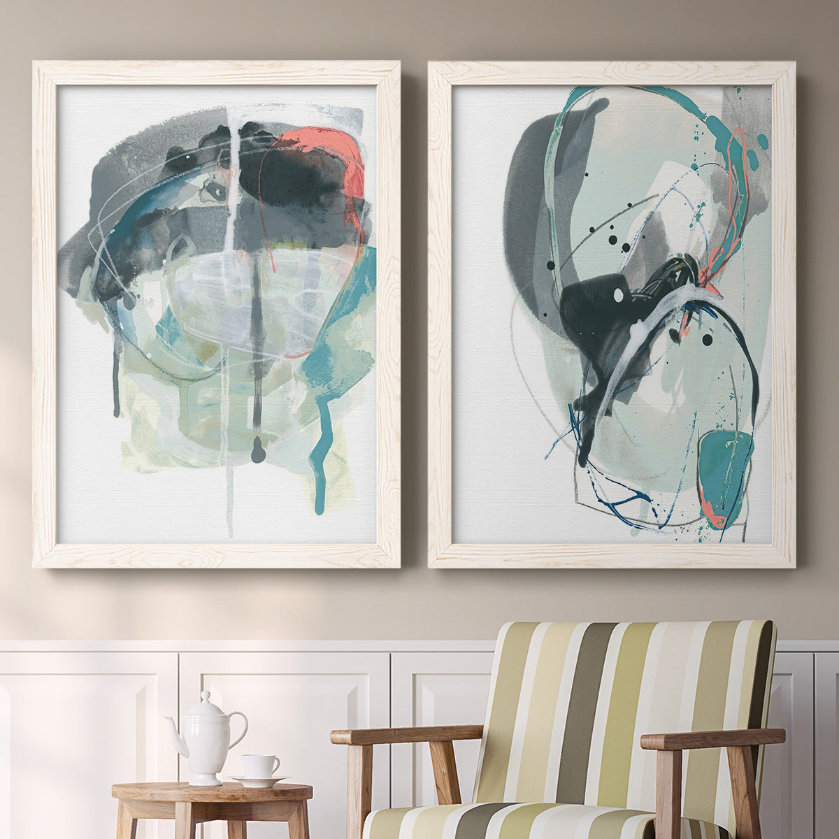 Set of two white barnwood framed canvas prints depicting two bold gestural abstracts featuring large black gray and teal circular gestures above a sideboard in a cozy sitting room.
