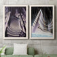 Set of two white barnwood framed canvas prints depicting a coordinated art pair of dramatic Art Deco city and theater scenes rendered as vintage architectural illustrations above a sofa in a modern living room.