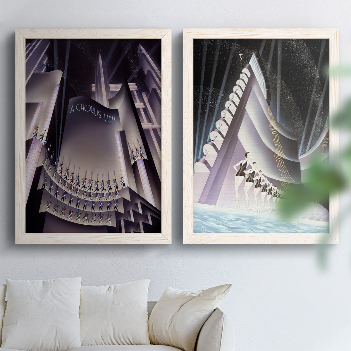 Set of two white barnwood framed canvas prints depicting monumental skyscrapers, sweeping stairways, spotlights, and elegant nighttime figures arranged across two complementary compositions above a sofa in a bright living space.
