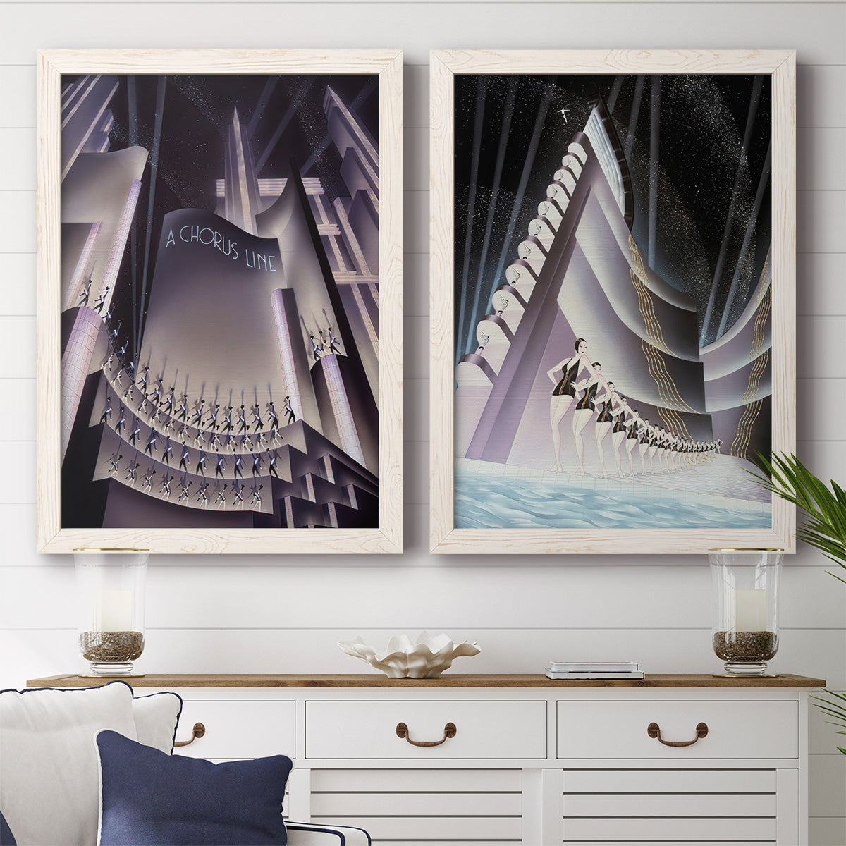Set of two white barnwood framed canvas prints depicting a coordinated art pair of dramatic Art Deco city and theater scenes rendered as vintage architectural illustrations above a dining room sideboard.