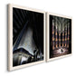 Angled view of a set of two white barnwood framed canvas prints featuring two vintage architectural illustrations featuring dramatic Art Deco city and theater scenes.