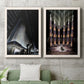 Set of two white barnwood framed canvas prints depicting a coordinated art pair of dramatic Art Deco city and theater scenes rendered as vintage architectural illustrations above a sofa in a modern living room.