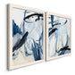 Angled view of a set of two white barnwood framed canvas prints featuring two expressive blue abstracts featuring sweeping indigo and black gestural brushwork.