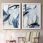 Set of two white barnwood framed canvas prints depicting two expressive blue abstracts featuring sweeping indigo and black gestural brushwork above a sideboard in a cozy sitting room.