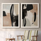 Set of two white barnwood framed canvas prints depicting two minimalist collage-like abstracts featuring black taupe cream and beige painted forms above a sideboard in a cozy sitting room.