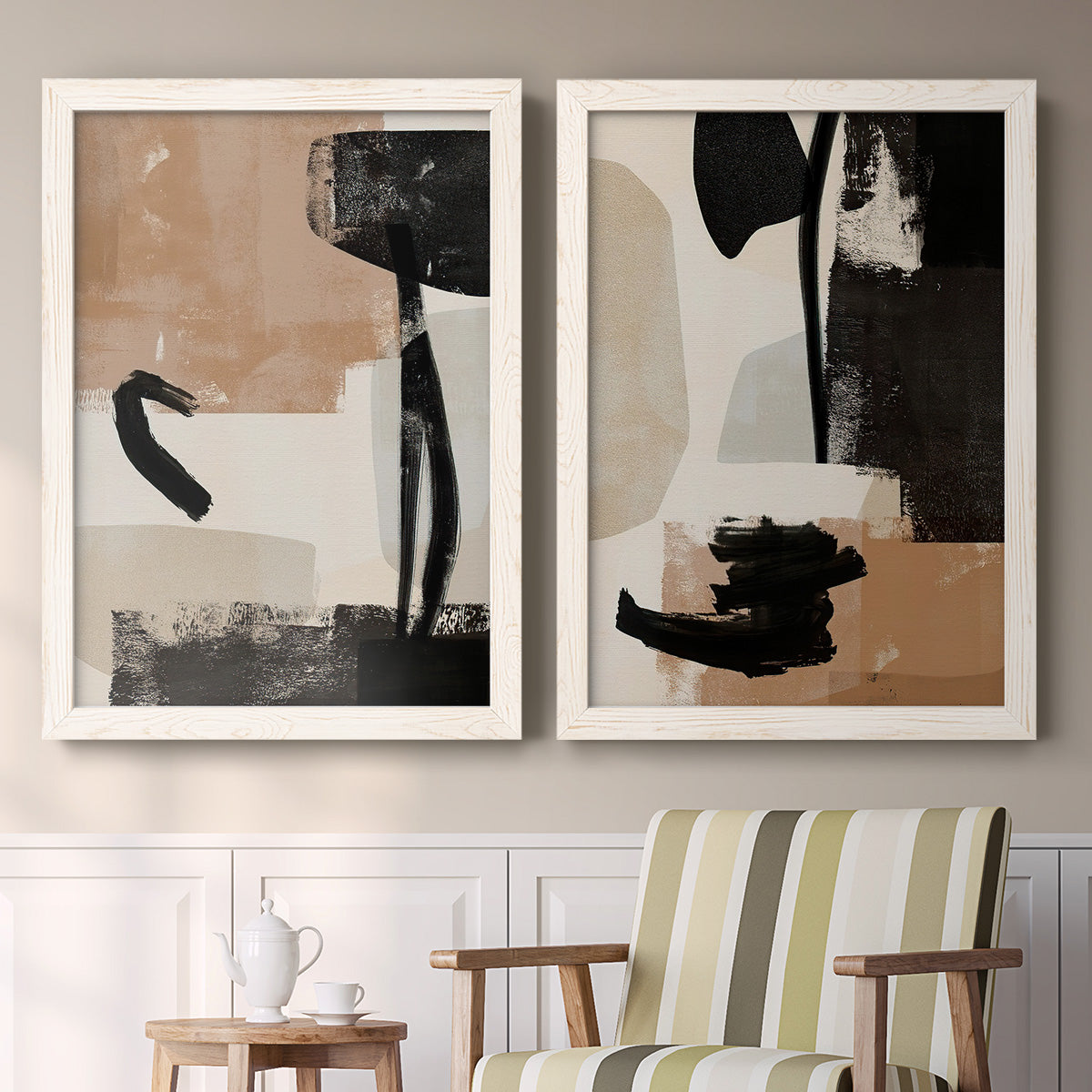 Set of two white barnwood framed canvas prints depicting two minimalist collage-like abstracts featuring black taupe cream and beige painted forms above a sideboard in a cozy sitting room.