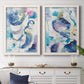 Set of two white barnwood framed canvas prints depicting a coordinated art pair of lively blue pink violet and turquoise watercolor gestures rendered as colorful lyrical abstracts above a dining room sideboard.