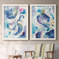 Set of two white barnwood framed canvas prints depicting two colorful lyrical abstracts featuring lively blue pink violet and turquoise watercolor gestures above a sideboard in a cozy sitting room.