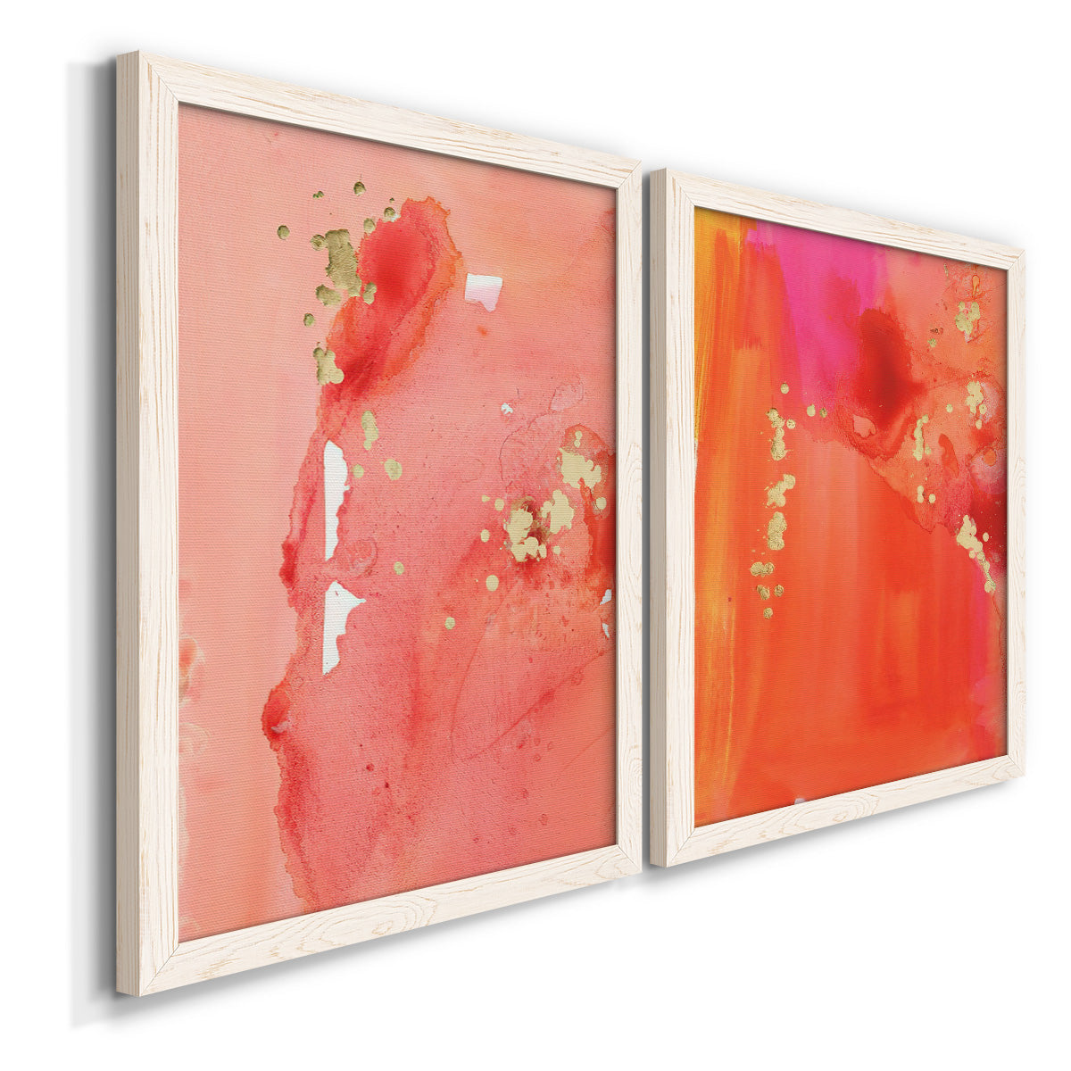 Angled view of a set of two white barnwood framed canvas prints featuring two glamorous fluid abstracts featuring luminous coral orange and pink color fields with gold flecks.