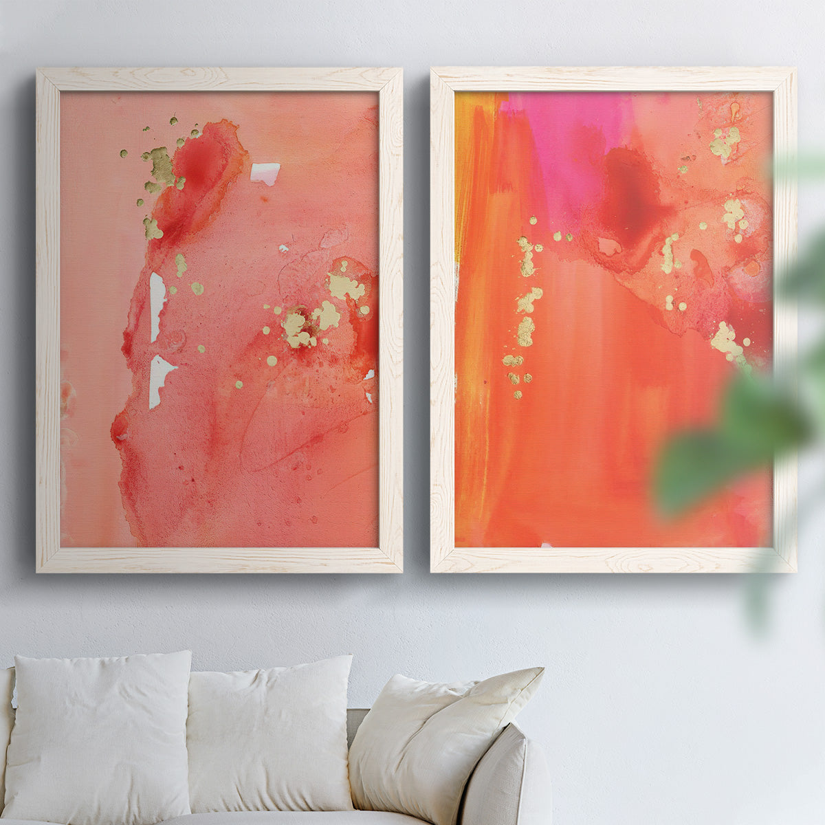 Set of two white barnwood framed canvas prints depicting translucent warm washes, drips, and scattered metallic accents arranged across two complementary compositions above a sofa in a bright living space.