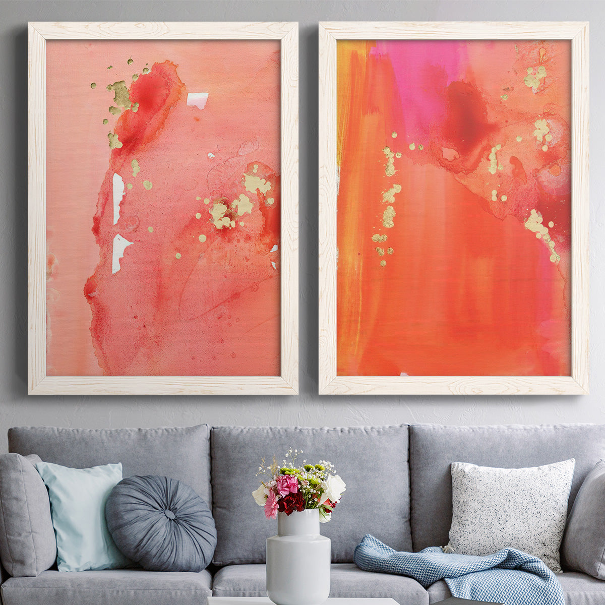 Set of two white barnwood framed canvas prints depicting paired glamorous fluid abstracts with translucent warm washes, drips, and scattered metallic accents above a sofa in a contemporary living room.