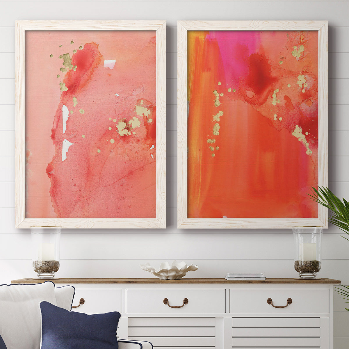 Set of two white barnwood framed canvas prints depicting a coordinated art pair of luminous coral orange and pink color fields with gold flecks rendered as glamorous fluid abstracts above a dining room sideboard.