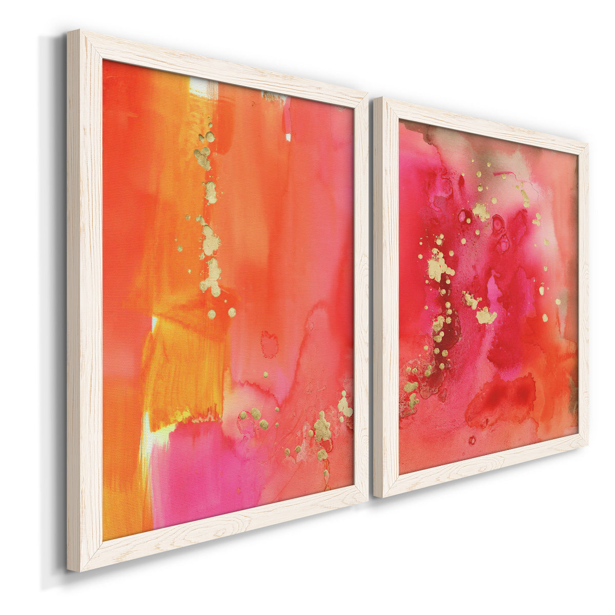Angled view of a set of two white barnwood framed canvas prints featuring two glamorous fluid abstracts featuring luminous coral orange and pink color fields with gold flecks.