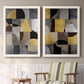 Set of two white barnwood framed canvas prints depicting two structured modern abstracts featuring interlocking black gray cream and gold geometric sections above a sideboard in a cozy sitting room.