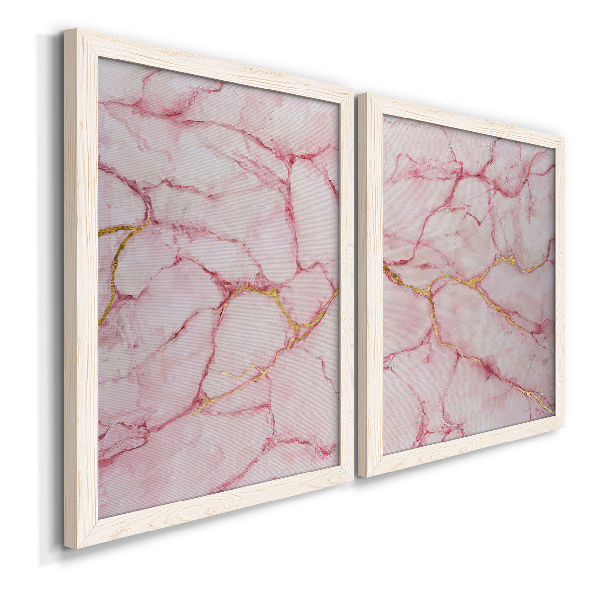 Angled view of a set of two white barnwood framed canvas prints featuring two soft stone-inspired abstracts featuring pink marble veining with fine gold lines.