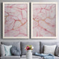Set of two white barnwood framed canvas prints depicting paired soft stone-inspired abstracts with blush mineral clouds, branching veins, and luminous pale grounds above a sofa in a contemporary living room.
