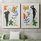 Set of two white barnwood framed canvas prints depicting stylized female figures surrounded by blue leaves green starbursts orange forms and gestural marks above a sofa in a modern living room.