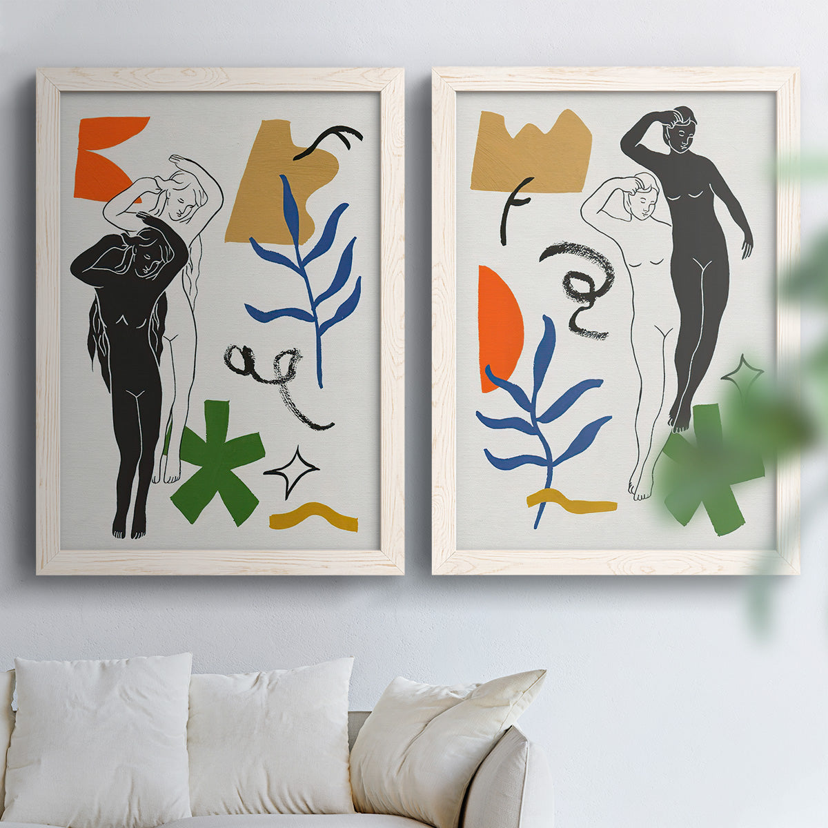 Set of two white barnwood framed canvas prints depicting a modern collage pair combining black and white women organic motifs and playful geometric accents above a sofa in a bright living space.